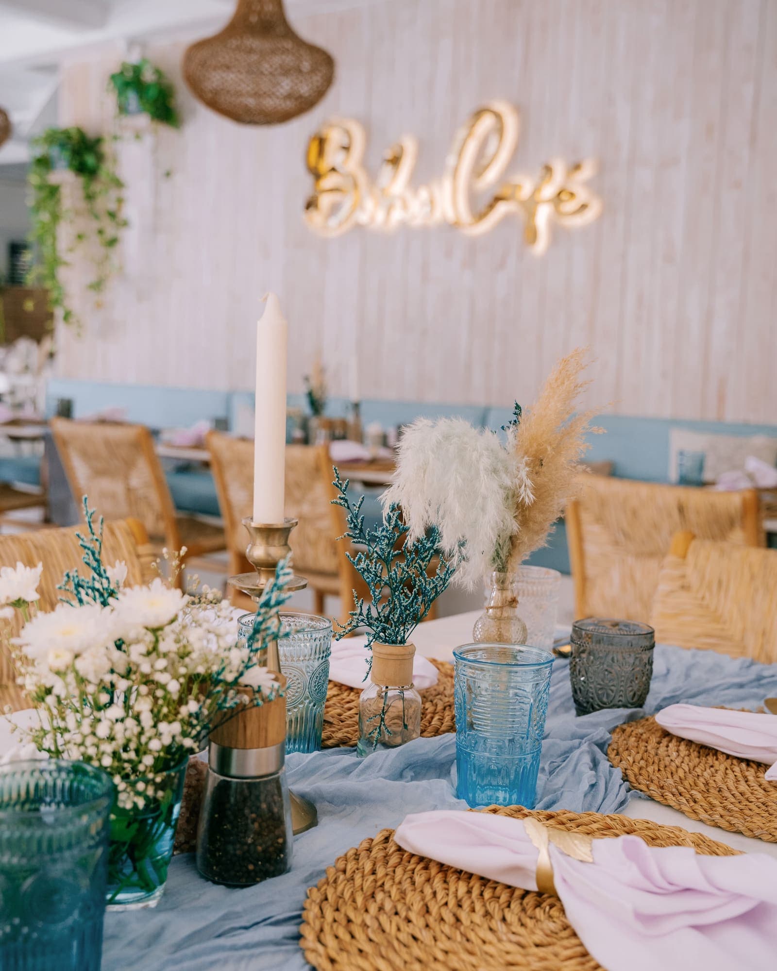 The Boho Café sign on a white wall above a table with pampas grass