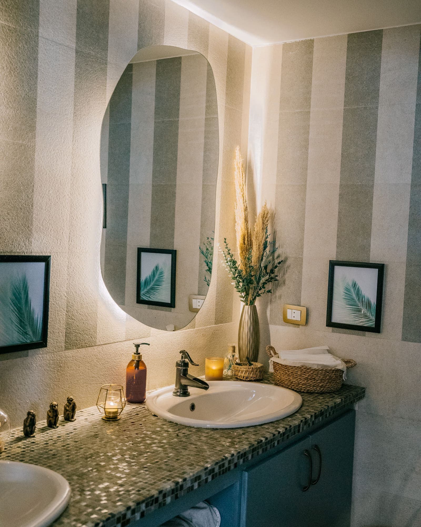 Washroom with an arched mirror, dried grasses and framed palm prints